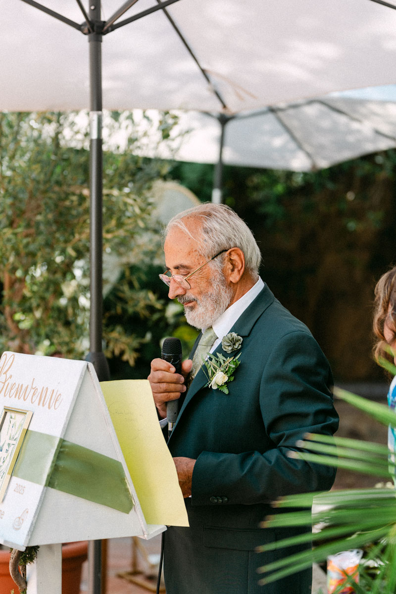 Homme en costume prononçant un discours au micro avec fleur à la boutonnière – photographe de mariage Pyrénées-Orientales