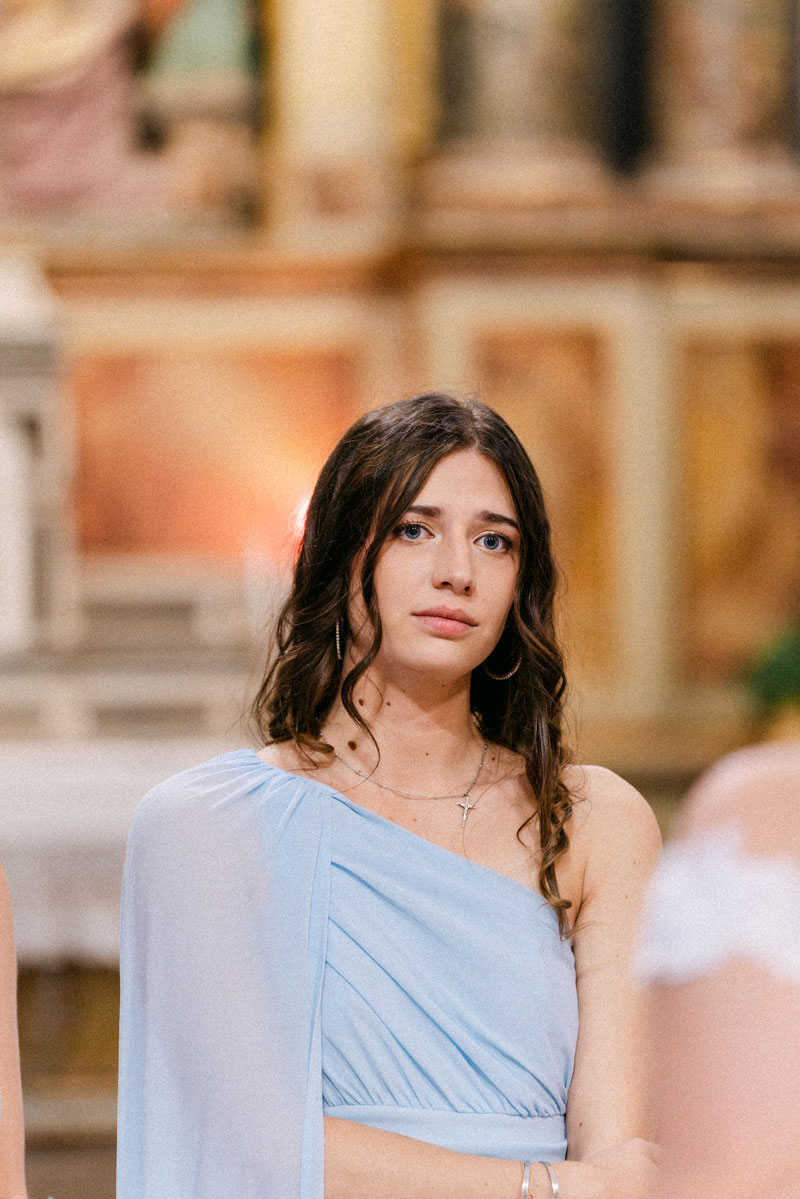Jeune femme en robe bleue posant devant une église avec plante en pot – photographe de mariage Pyrénées-Orientales